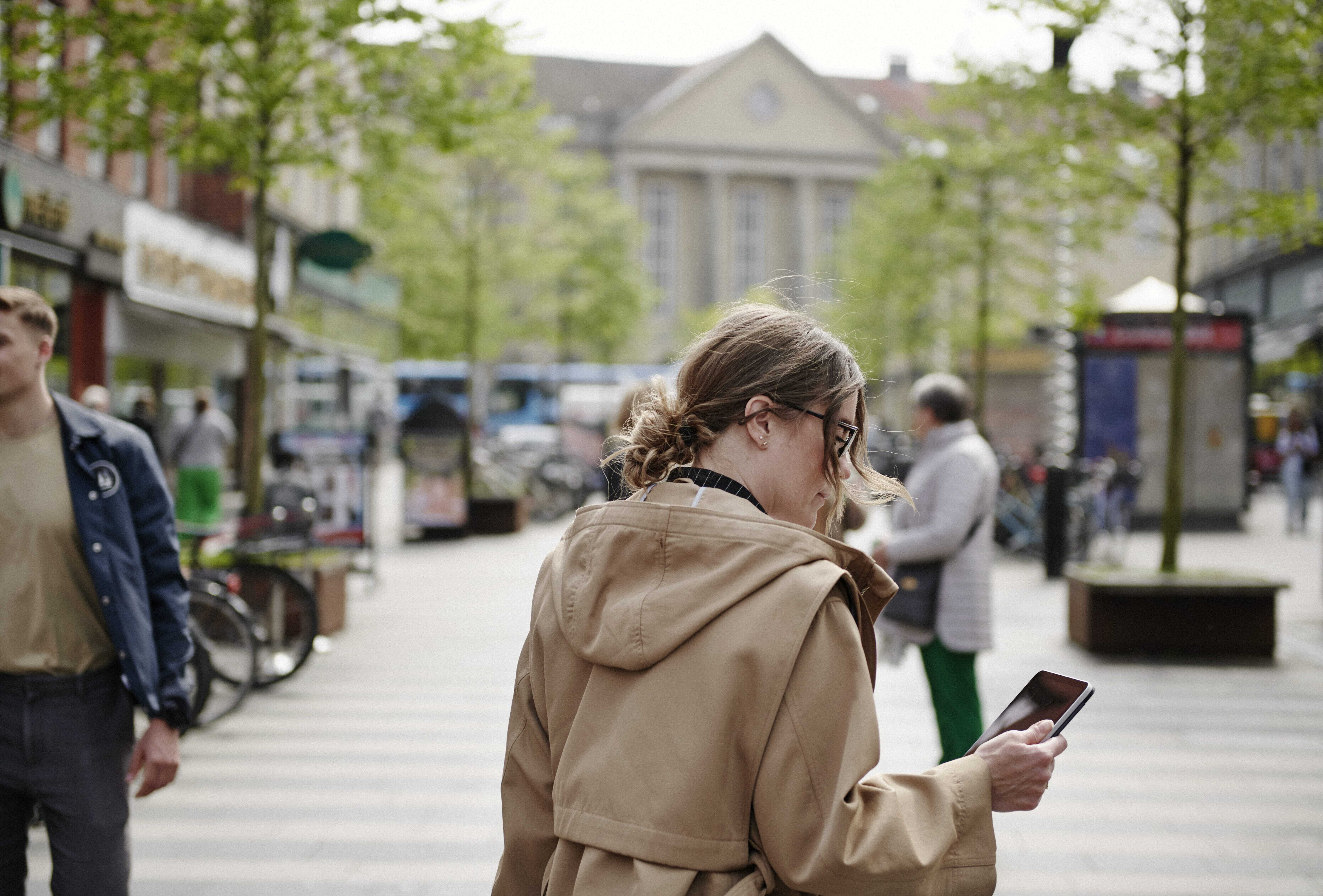 Kvinde med tablet i hånden på en travl bymidte