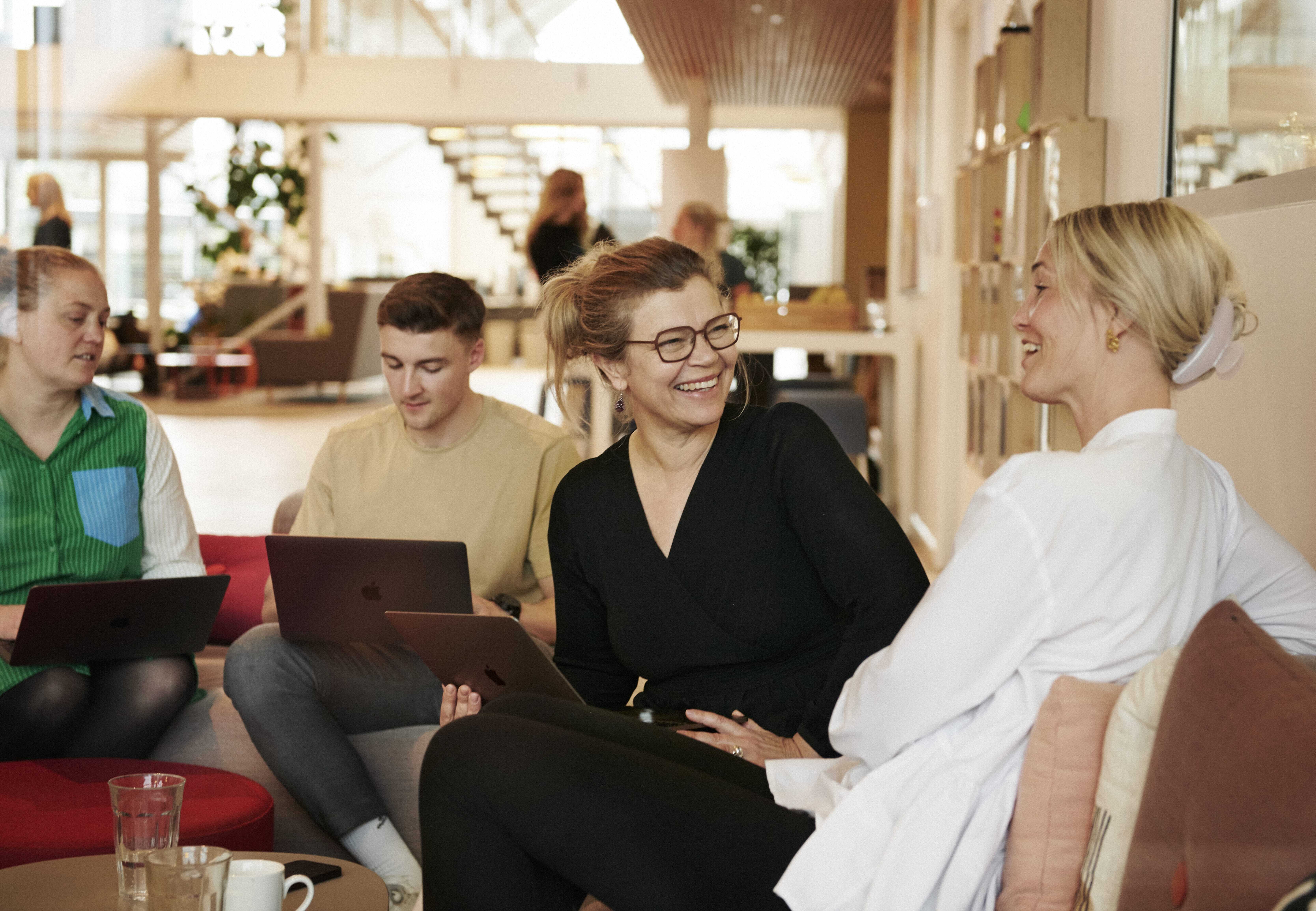 Kolleger i uformel faglig dialog i moderne kontormiljø